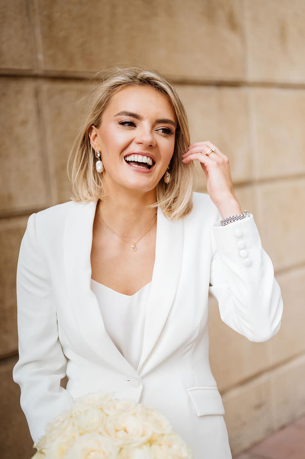 Brighton wedding photography. Bride wearing white suit photographed on a  Brighton street 